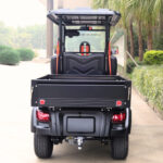 Rear image of the medium bed, four-seater, black Fusion commercial utility vehicle parked outside of a building.