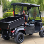 Black, two-seater, short bed Fusion commercial utility vehicle showing off the rear dumping capabilities in action.