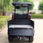 Rear image of the short bed, two-seater, black Fusion commercial utility vehicle parked outside of a building.